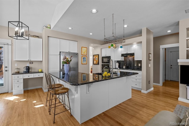 kitchen with white cabinetry, an island with sink, a breakfast bar area, black appliances, and light hardwood / wood-style flooring