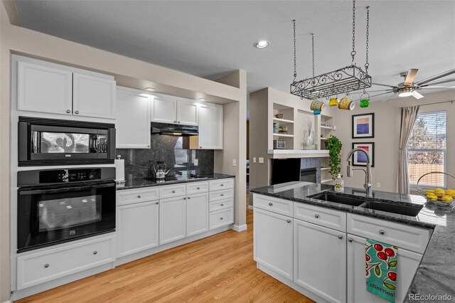 kitchen with sink, dark stone countertops, white cabinets, light hardwood / wood-style floors, and black appliances