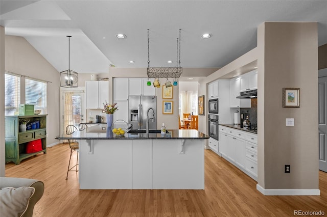 kitchen featuring sink, a breakfast bar, black appliances, an island with sink, and white cabinets