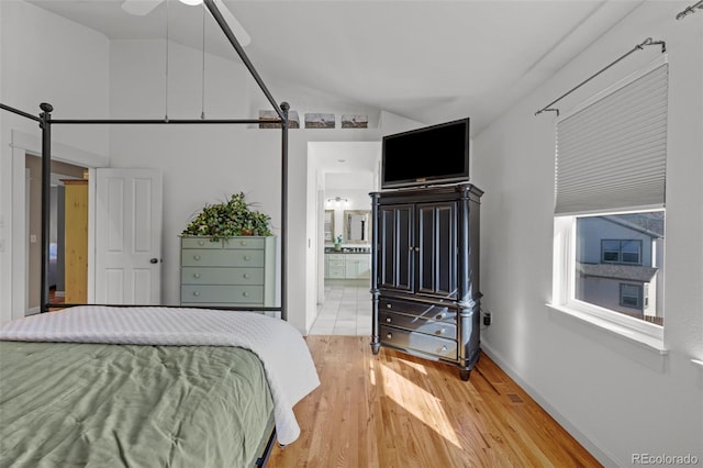 bedroom with connected bathroom, vaulted ceiling, and wood-type flooring