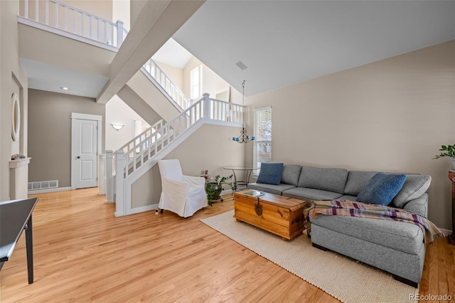 living room with a towering ceiling, a chandelier, and hardwood / wood-style floors