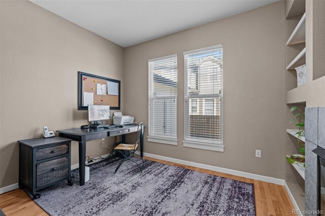 office area featuring hardwood / wood-style flooring and a tiled fireplace