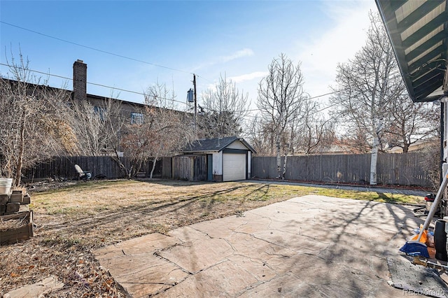 view of yard with a garage, a patio, and an outbuilding