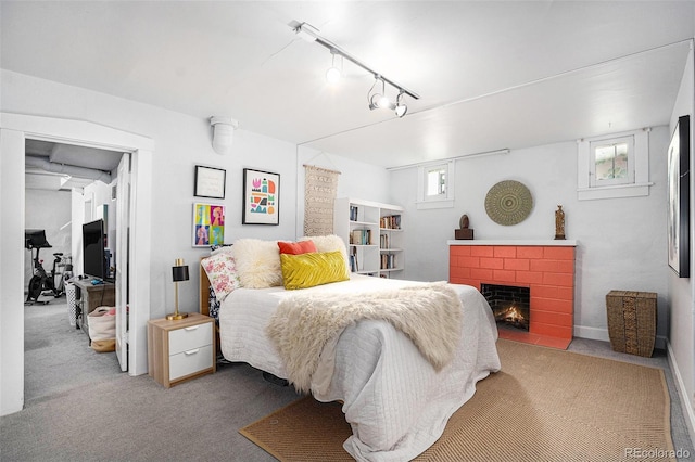 bedroom featuring multiple windows, a fireplace, rail lighting, and carpet flooring