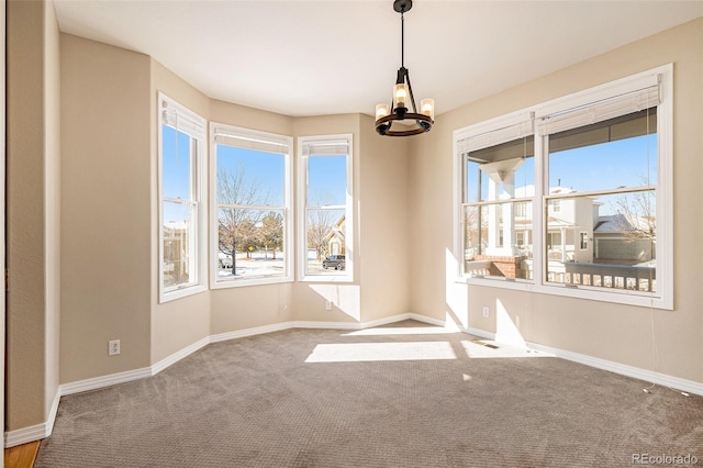 carpeted spare room with a notable chandelier