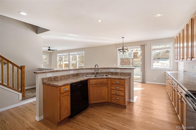 kitchen with pendant lighting, dishwasher, stove, sink, and light hardwood / wood-style flooring