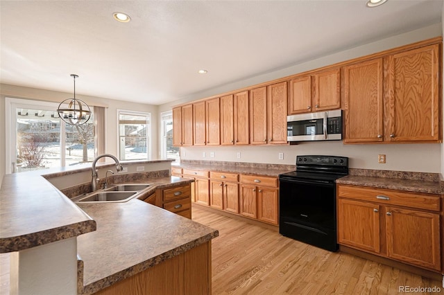 kitchen featuring sink, black range with electric cooktop, a chandelier, decorative light fixtures, and a kitchen island with sink