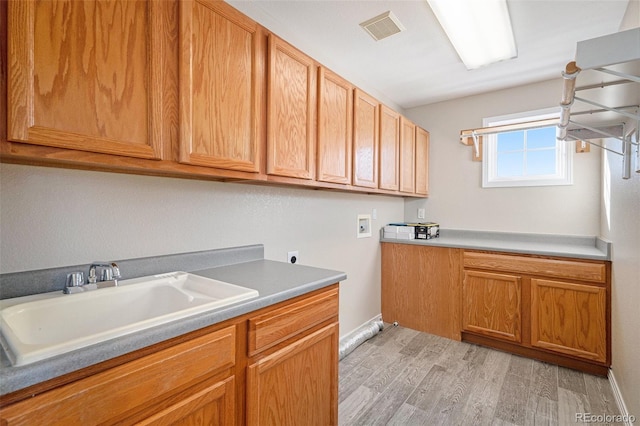 clothes washing area featuring electric dryer hookup, cabinets, sink, light hardwood / wood-style flooring, and washer hookup