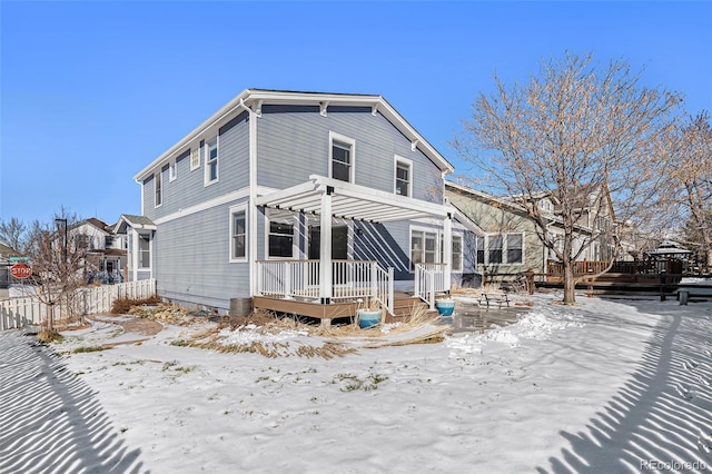 snow covered back of property with a deck