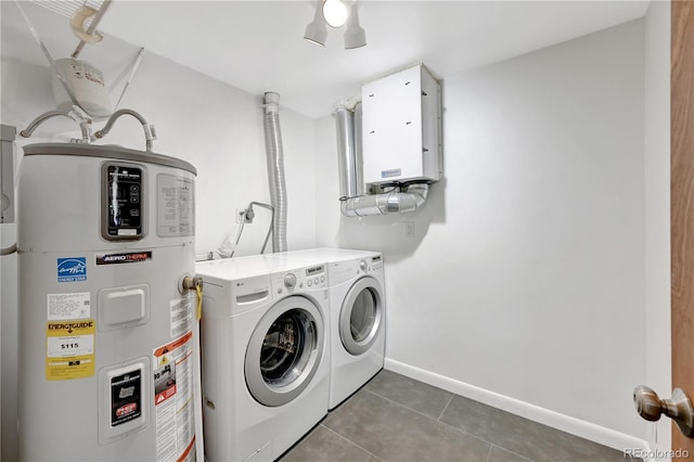 laundry area with hybrid water heater, laundry area, dark tile patterned floors, baseboards, and washer and dryer