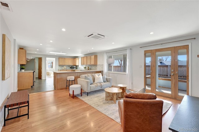 living area featuring light wood-type flooring, visible vents, and recessed lighting