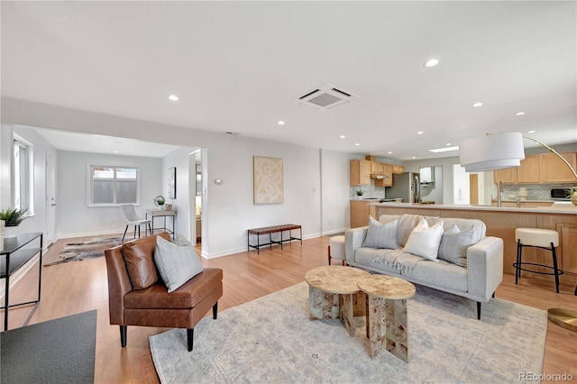 living area featuring light wood-type flooring, visible vents, and recessed lighting