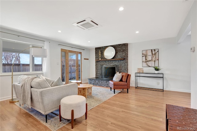 living area with light wood-type flooring, a brick fireplace, visible vents, and recessed lighting