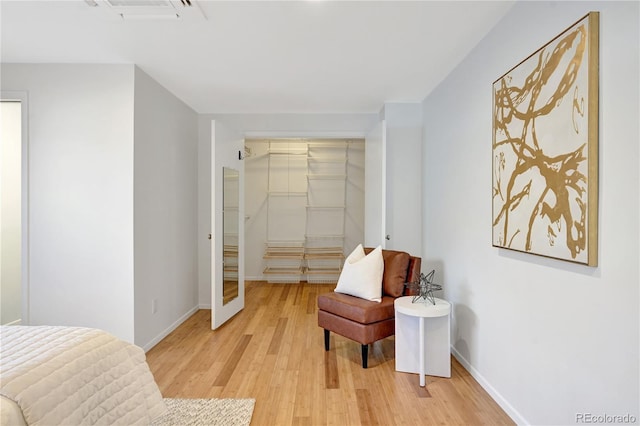 bedroom with light wood-style flooring, visible vents, baseboards, a closet, and a walk in closet