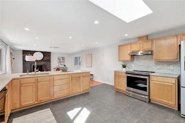 kitchen featuring appliances with stainless steel finishes, light countertops, under cabinet range hood, light brown cabinets, and a sink