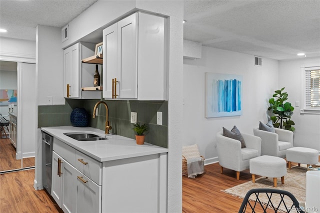 7615 E Quincy Ave Unit 103, Denver, CO 80237 - kitchen featuring a textured ceiling, light wood-type flooring, light countertops, recessed lighting, and backsplash