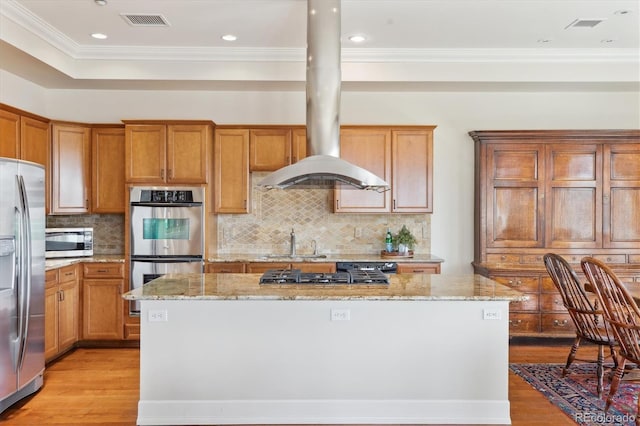 kitchen with light wood finished floors, visible vents, light stone countertops, appliances with stainless steel finishes, and a kitchen island
