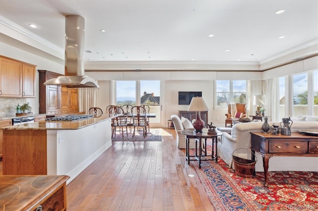 living room with a wealth of natural light, baseboards, ornamental molding, and light wood-type flooring