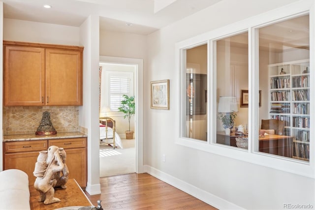hallway with light wood finished floors, baseboards, and recessed lighting