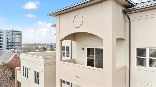 view of property exterior featuring a balcony, a standing seam roof, and stucco siding