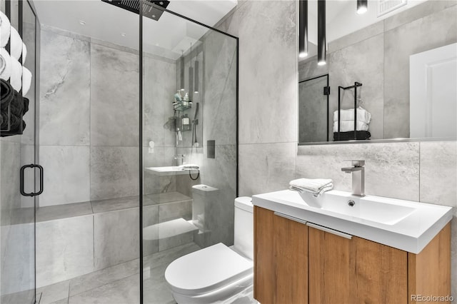 bathroom featuring vanity, toilet, a shower with door, and tile walls