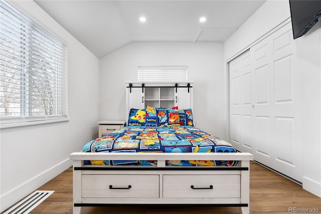 bedroom with hardwood / wood-style flooring, a closet, and lofted ceiling