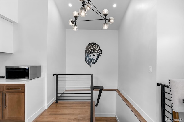 stairs featuring wood-type flooring and a notable chandelier