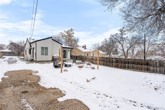 snow covered back of property with a fire pit