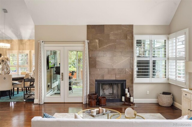 7836 S Fairfax Ct, Centennial, CO 80122 - living room with french doors, a tiled fireplace, vaulted ceiling, wood finished floors, and baseboards