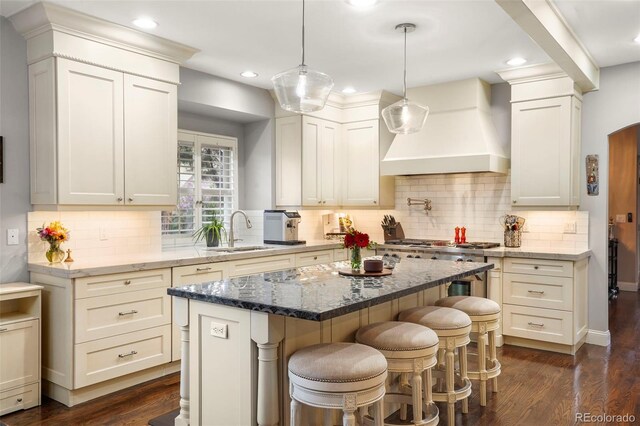 7836 S Fairfax Ct, Centennial, CO 80122 - kitchen featuring custom exhaust hood, a kitchen island, a breakfast bar, a sink, and dark wood finished floors