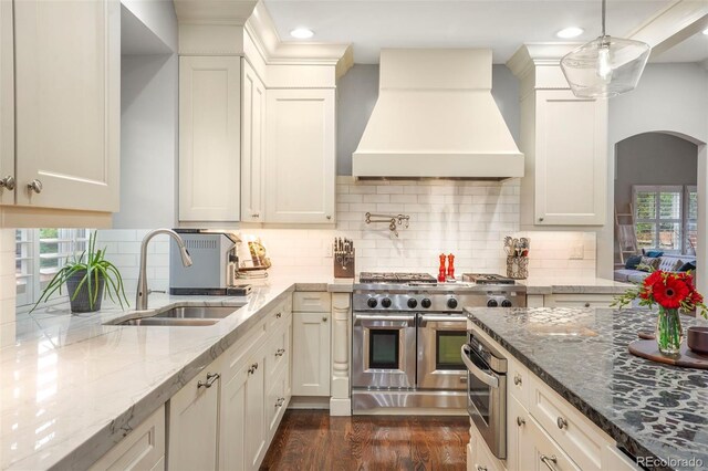 7836 S Fairfax Ct, Centennial, CO 80122 - kitchen with arched walkways, light stone countertops, a sink, custom exhaust hood, and stainless steel appliances