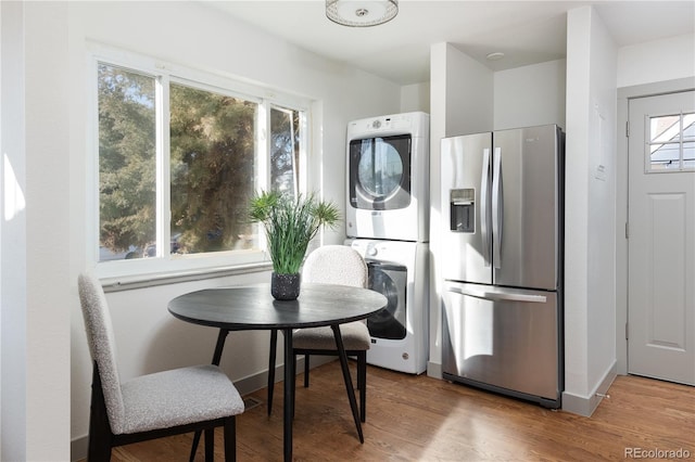 kitchen featuring stainless steel fridge, stacked washer and clothes dryer, and wood-type flooring