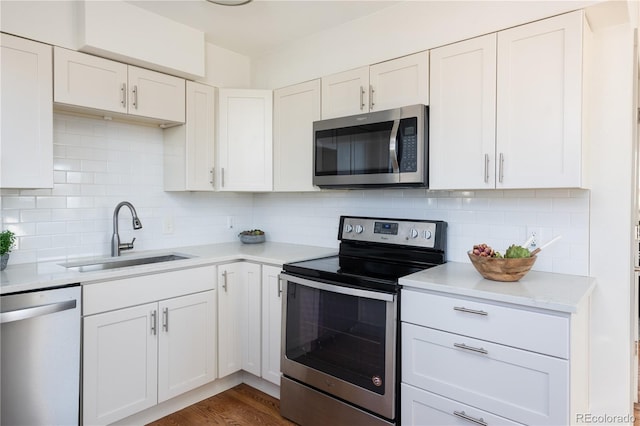 kitchen with sink, white cabinetry, dark hardwood / wood-style flooring, stainless steel appliances, and backsplash