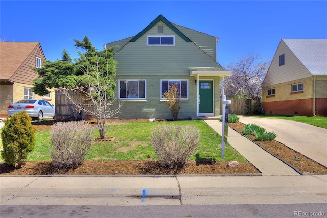 view of front of house featuring brick siding, a front lawn, and fence