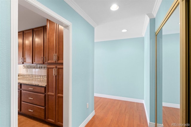 hallway featuring ornamental molding and light hardwood / wood-style floors