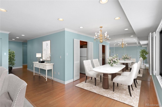 dining area with hardwood / wood-style flooring, ornamental molding, and a chandelier