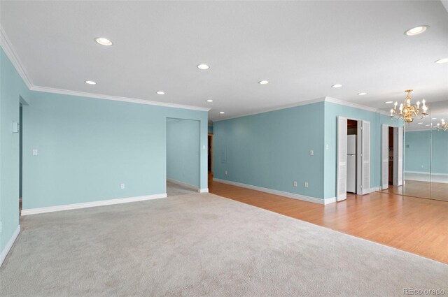 carpeted empty room featuring crown molding and a notable chandelier