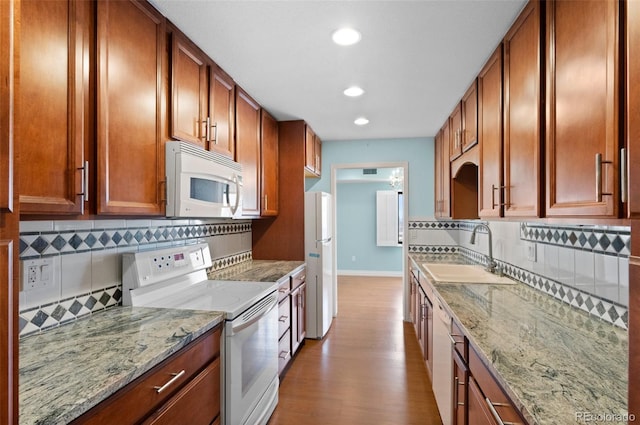 kitchen featuring white appliances, light hardwood / wood-style flooring, sink, light stone countertops, and tasteful backsplash