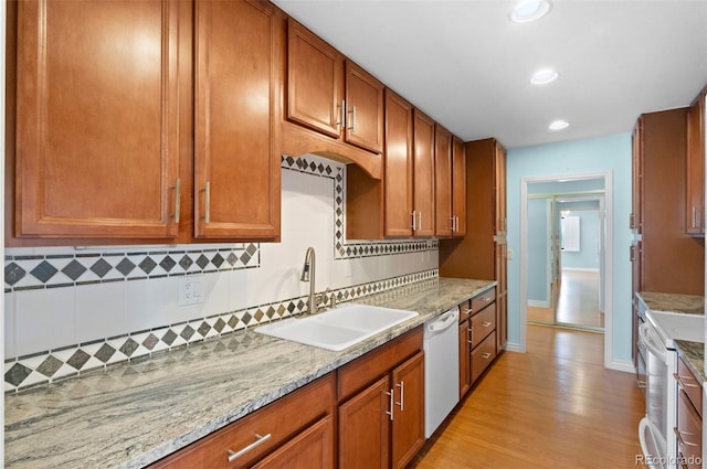 kitchen with white appliances, sink, light stone countertops, and decorative backsplash