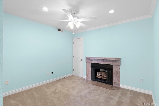 unfurnished living room featuring a fireplace, ceiling fan, crown molding, and light colored carpet