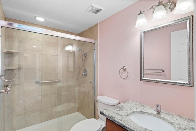 bathroom with toilet, a shower with door, and vanity