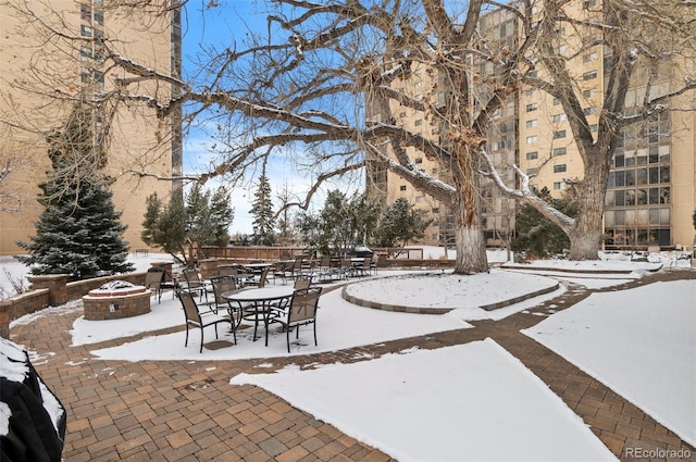 snow covered patio featuring an outdoor fire pit