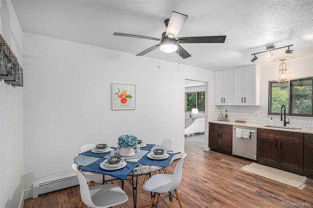 kitchen featuring decorative light fixtures, light countertops, white cabinets, a sink, and dishwasher