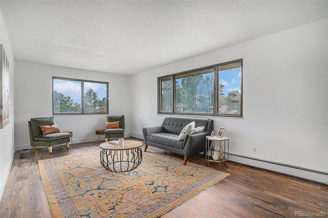 living area with a textured ceiling, baseboard heating, dark wood finished floors, and a wealth of natural light