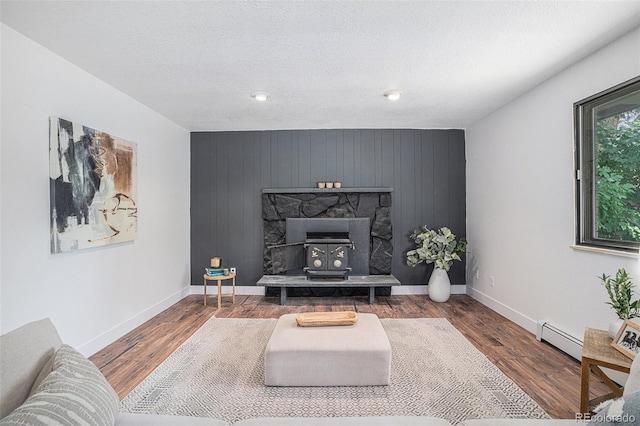 living area featuring a wood stove, a baseboard radiator, baseboards, and dark wood finished floors