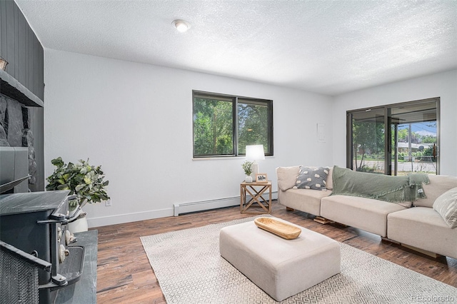 living room with a baseboard radiator, dark wood-style flooring, a healthy amount of sunlight, and a textured ceiling