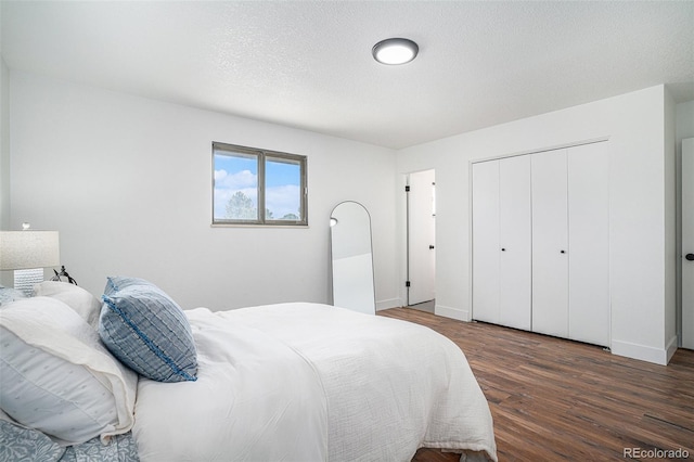 bedroom with dark wood-style floors, a textured ceiling, baseboards, and a closet