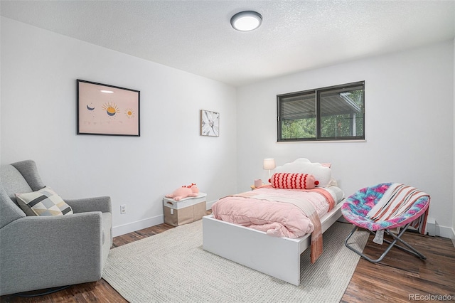 bedroom featuring a textured ceiling, dark wood-style flooring, and baseboards