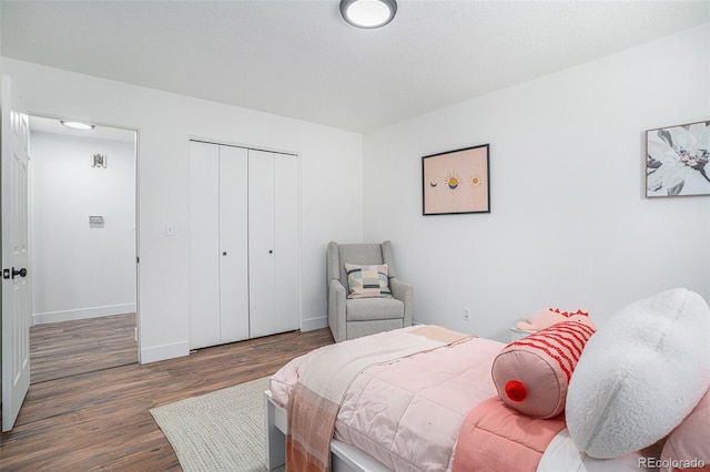 bedroom featuring a closet, baseboards, and dark wood-type flooring