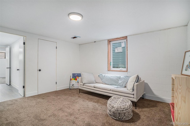 sitting room featuring carpet floors, visible vents, and concrete block wall